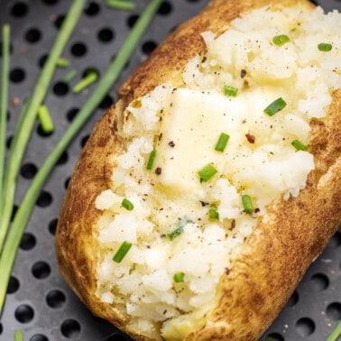 Overhead view looking into an air fryer basket with a baked potato inside.