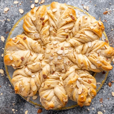 Overhead view of a loaf of Almond Star Bread surrounded by loosely scattered slivered almonds.