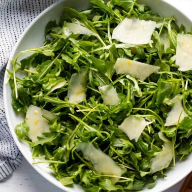 Bird's eye view of arugula salad in a white bowl.