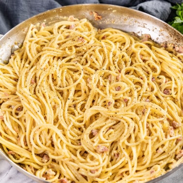 A close up view of a skillet full of pasta carbonara.