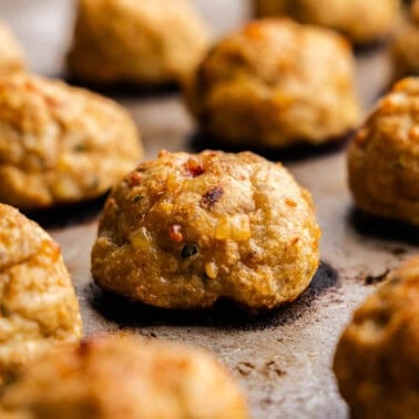 A close up of baked chicken meatballs on a baking sheet.