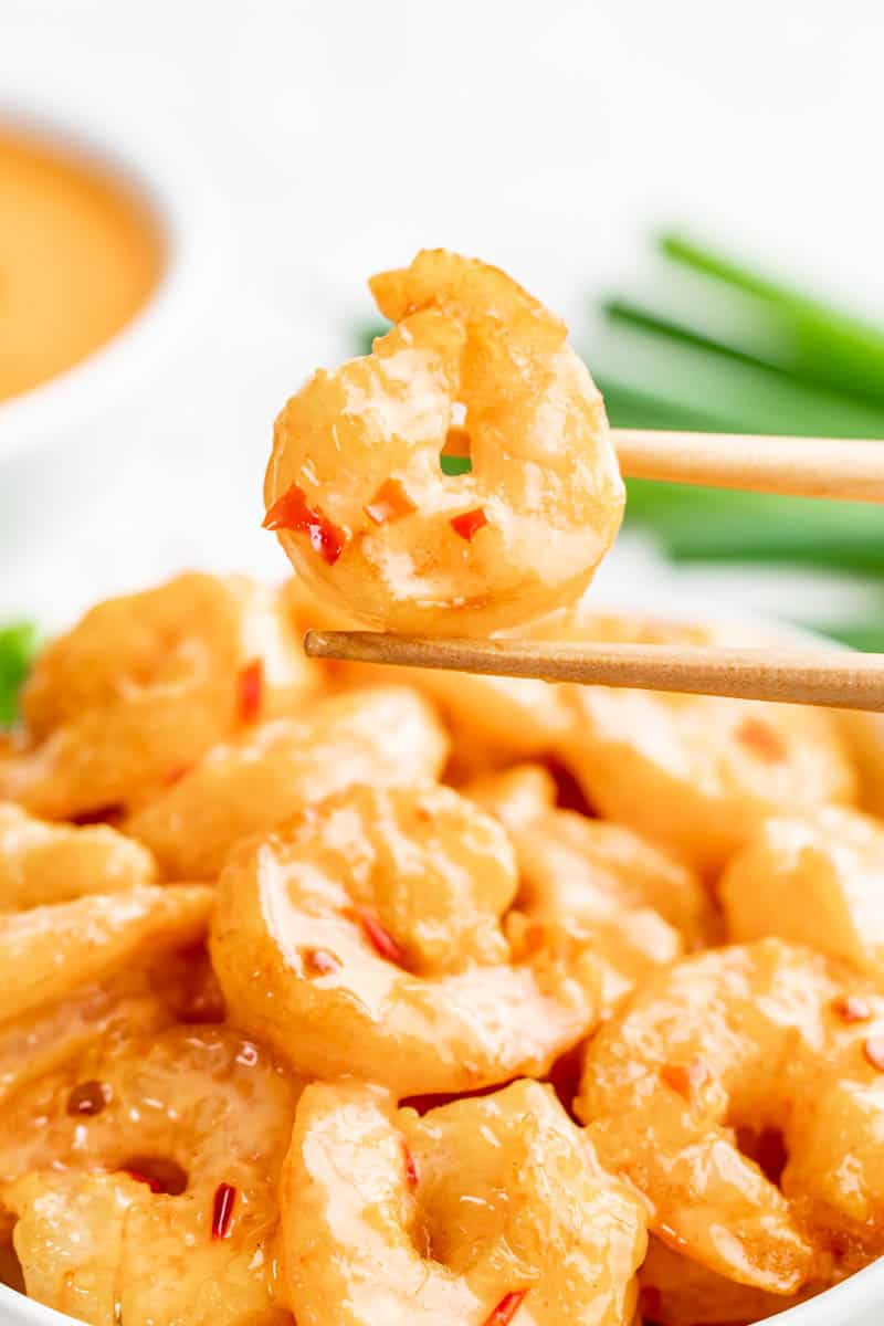 Chopsticks holding a piece of bang bang shrimp.