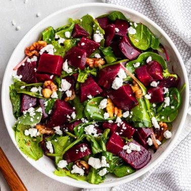 An overhead birds-eye view of a bowl of beet salad with nuts and feta cheese crumbles.