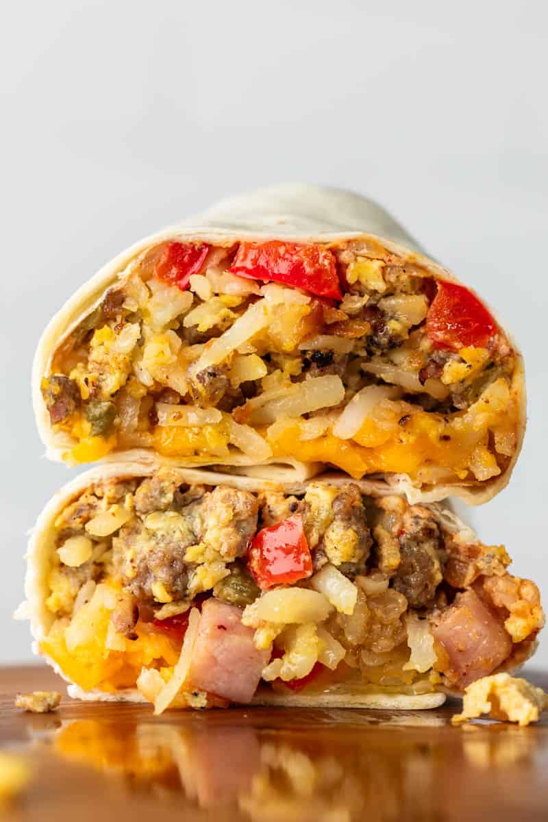 A breakfast burrito cut in half, with the two halves stacked on top of each other.