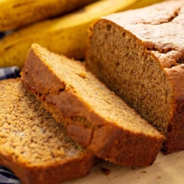 Banana Bread with two slices taken off the end, laying on each other all on a cutting board.