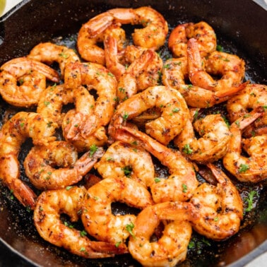 Overhead view of cajun shrimp on a black plate.