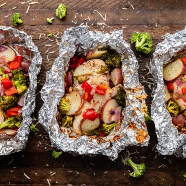 Three cheesy ranch chicken foil packets laid out on a table.