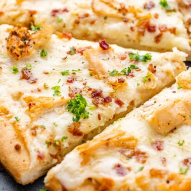 Close up view of chicken alfredo pizza.