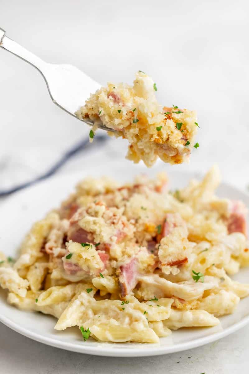 A fork holding up a bite's worth of chicken cordon bleu casserole.