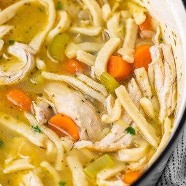 Close up overhead view of chicken noodle soup in a large pot.