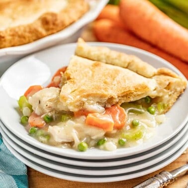 a slice of chicken pot pie on a white plate with filling oozing out.