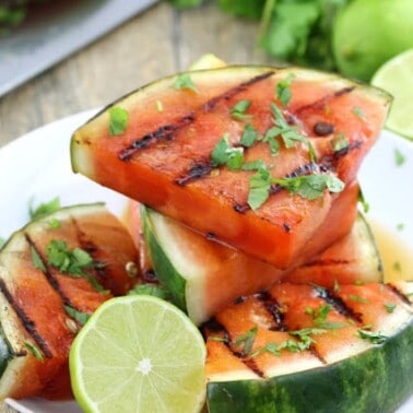 Grilled Watermelon on a white plate with half a lime.