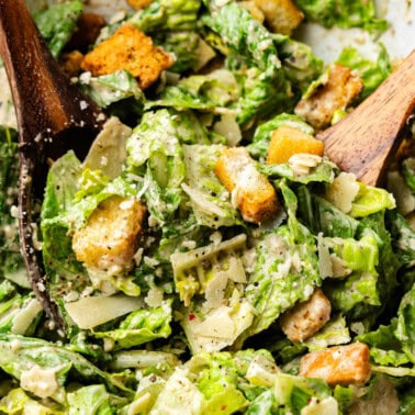 A large bowl of Caesar Salad with a wooden spoon.