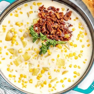 Bird's eye view of Corn chowder topped with bacon and parsley in a large cast iron pot.