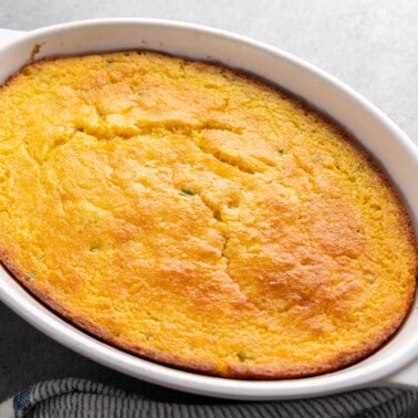 A whole corn casserole in a white baking dish.