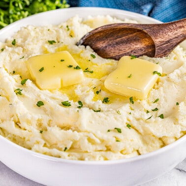 A large bowl of creamy mashed potatoes with butter on top.