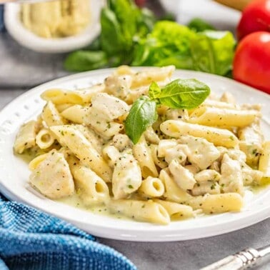 Chicken pesto pasta on a white dinner plate.