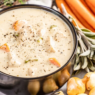 A black bowl filled with creamy chicken soup.