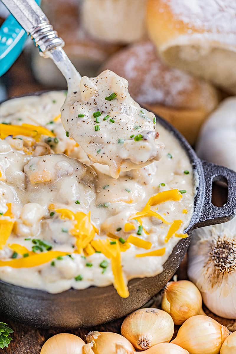 A spoon filled with creamy sausage potato soup.