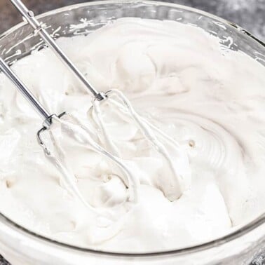 A glass bowl with beaters filled with 7 minute frosting.