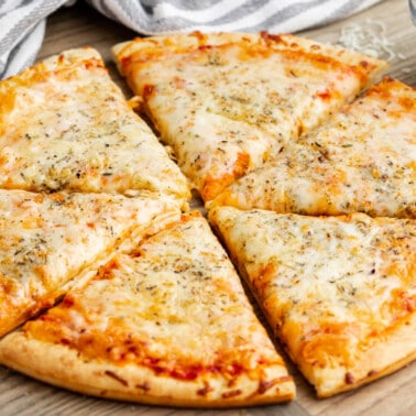 A cheese pizza on a cutting board, cut into 6 pieces.