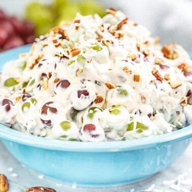 A full bowl of creamy grape salad with pecans and coconut.