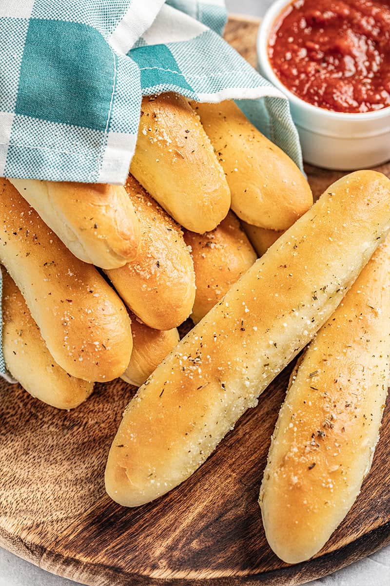 Homemade breadsticks on a wooden platter.