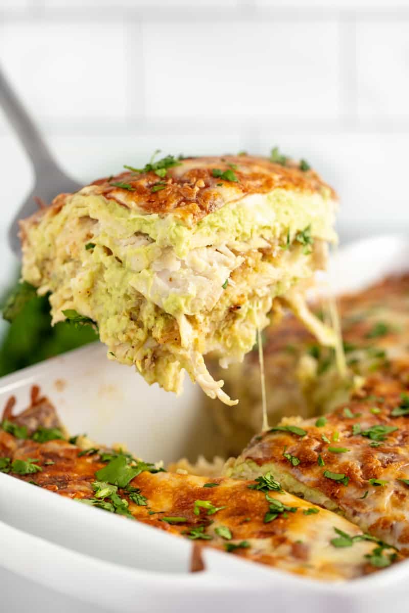 Slice of Chicken Enchilada Casserole being pulled out of the pan by a spatula.