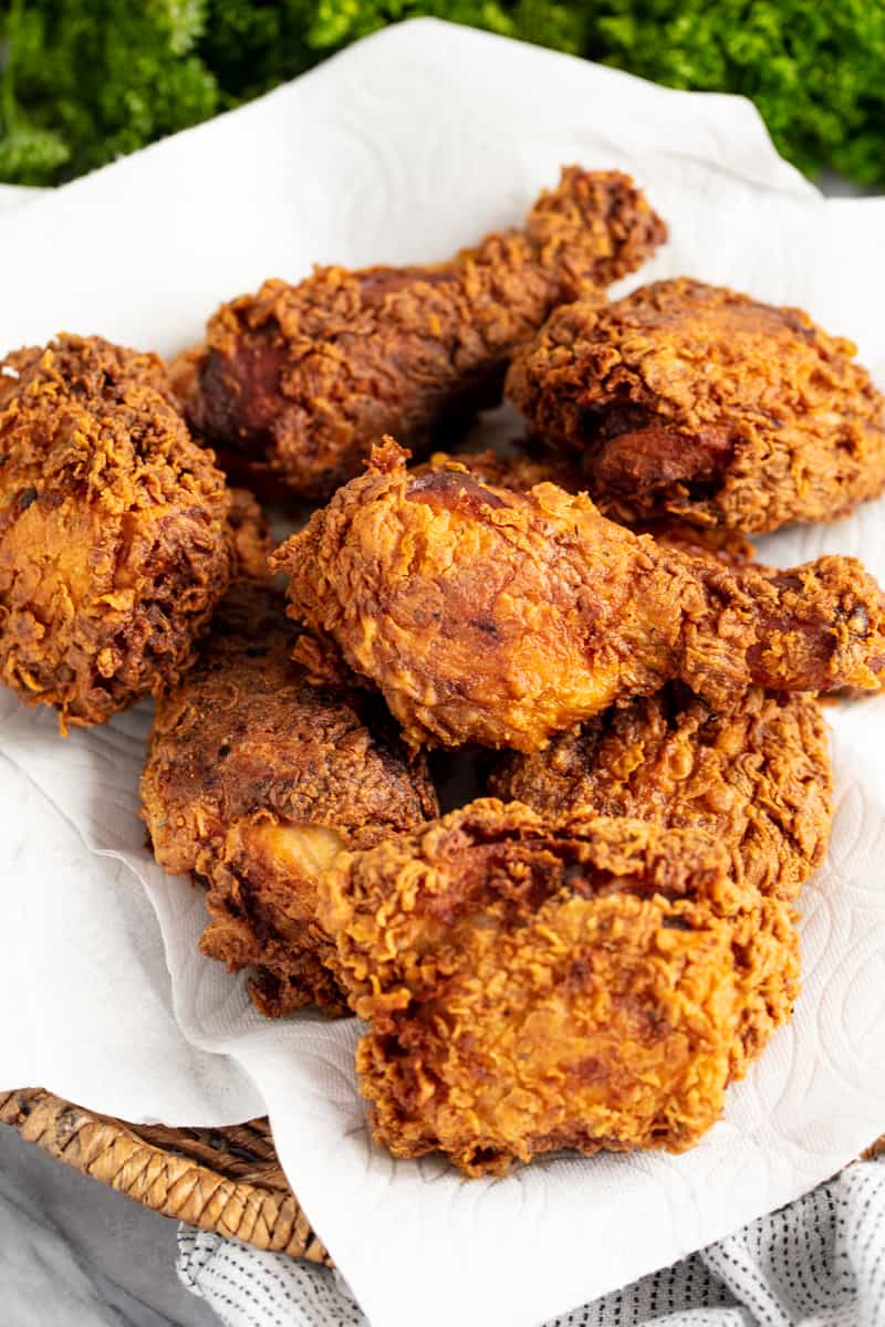 Bird's eye view Crispy Fried Chicken on a paper towel on a wood plate.