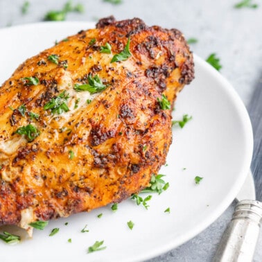 A chicken breast on a dinner plate that was cooked in the air fryer from frozen.