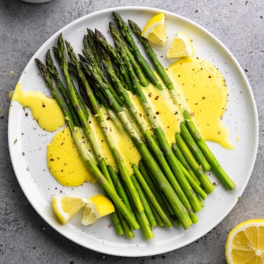 Overhead view of asparagus with hollandaise sauce drizzled on top.