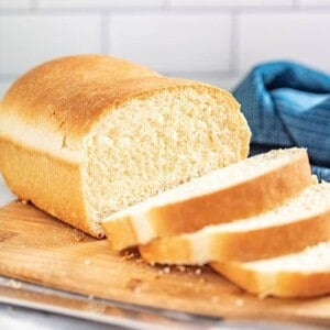 A loaf of homemade bread on a cutting board that has already been partially sliced.