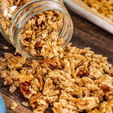 A glass jar on its side with homemade granola coming out.