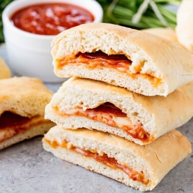 A stack of Homemade Hot Pockets filled with pepperoni, mozzarella and marinara sauce, set on a concrete countertop.