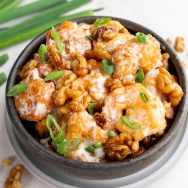 Honey walnut shrimp in a dark ceramic bowl.