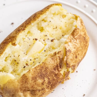 Overhead view of a baked potato split open with butter inside.