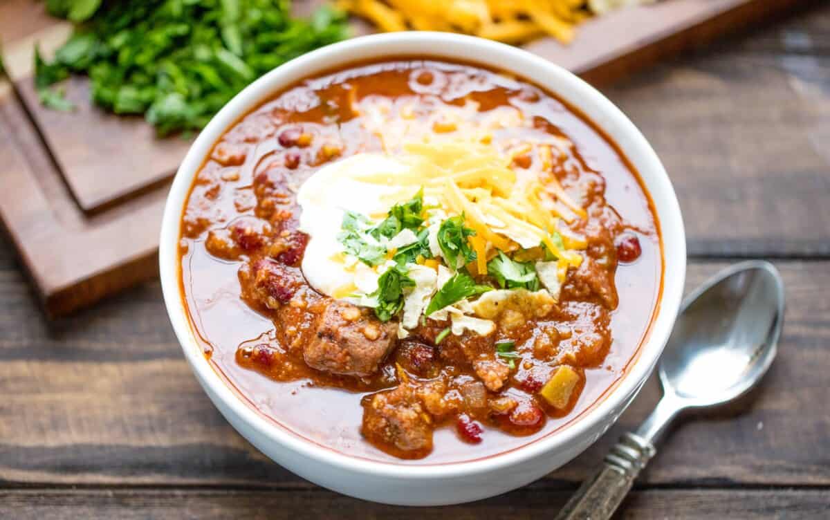 A bowl of Instant Pot Chili topped with sour cream, grated cheddar cheese and cilantro