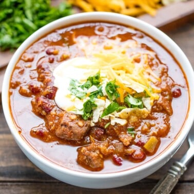 A bowl of Instant Pot Chili topped with sour cream, grated cheddar cheese and cilantro