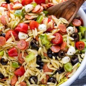 Italian Pasta Salad in a white bowl with a wooden spoon in it.