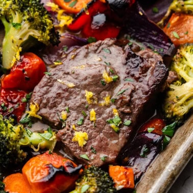 A close up overhead view of a sheet pan of Italian steak and veggies.