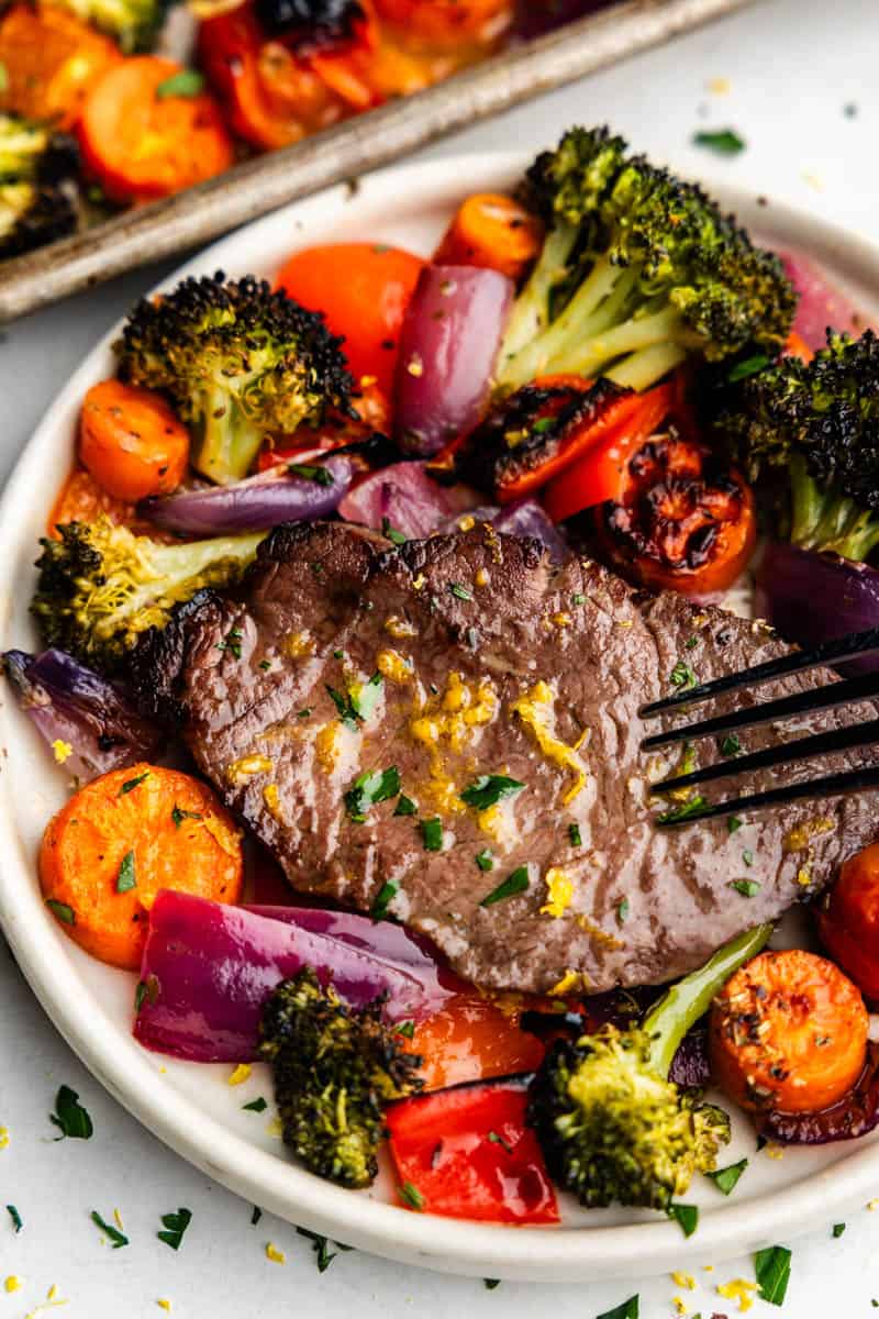 An overhead closeup view of a steak on a plate surrounded by a colorful array of vegetables.