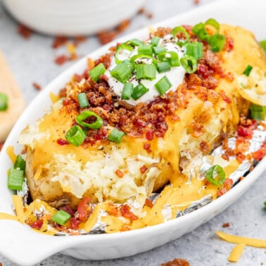 A loaded baked potato in a ceramic dish.