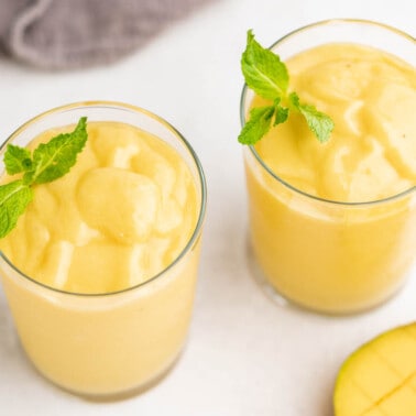 Overhead view, looking into glasses with mango smoothies.