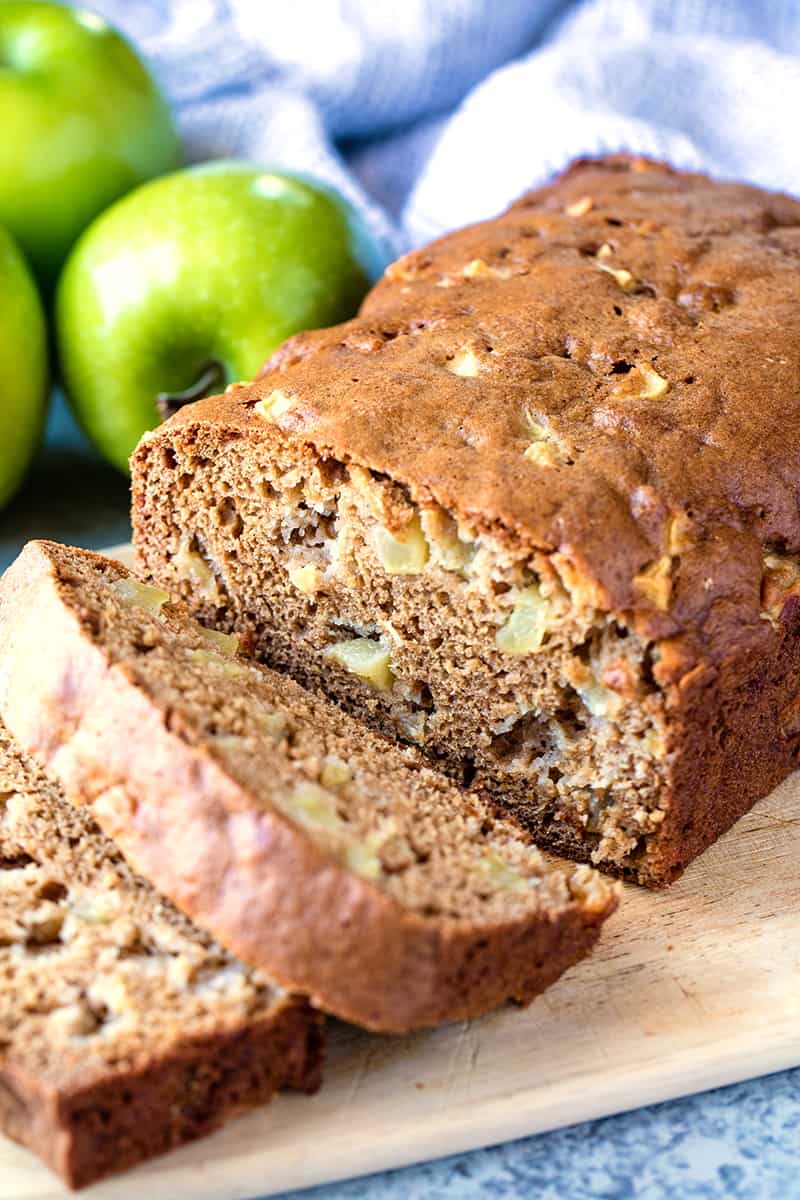 Sliced loaf of moist cinnamon apple bread on a cutting board.