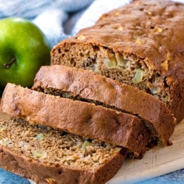 Sliced loaf of moist cinnamon apple bread on a cutting board.