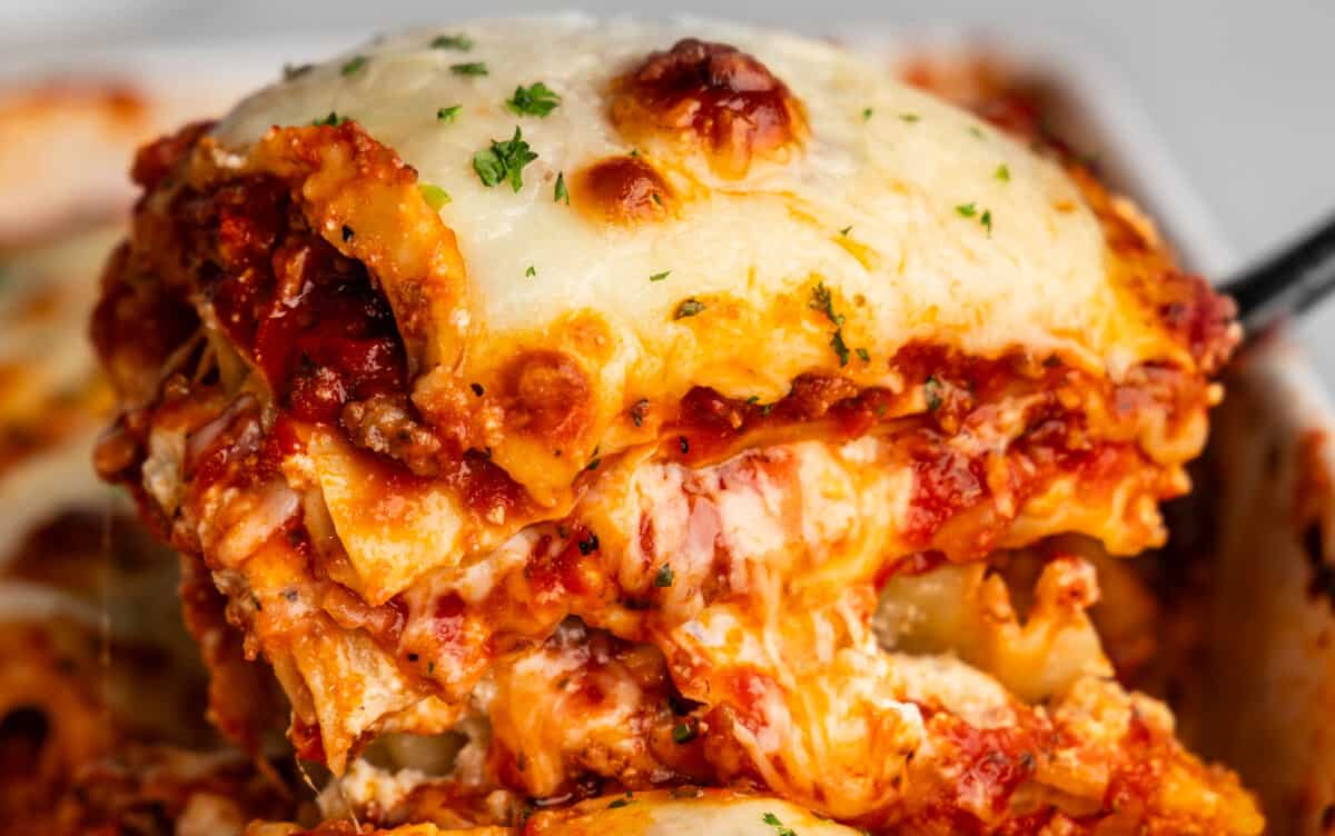 A helping of lasagna being dished out of a pan with a spatula.