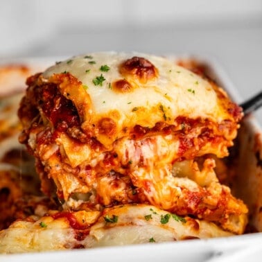 A helping of lasagna being dished out of a pan with a spatula.