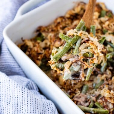 A scoop of green bean casserole above a dish of green bean casserole.