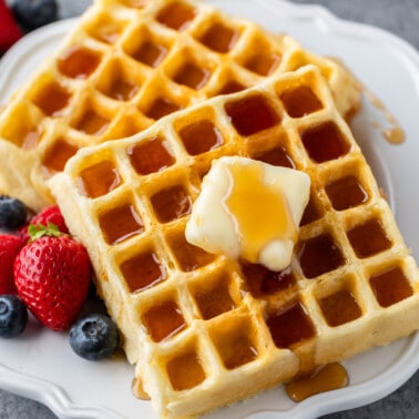 Homemade waffles on a white plate with berries.