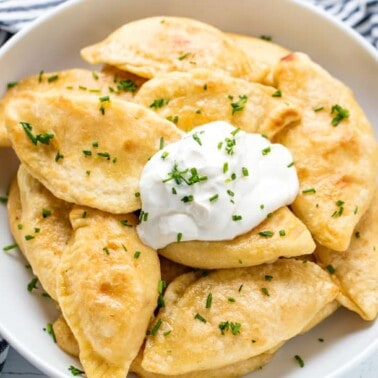 Potato and Cheese Pierogis in a bowl with a dollop of sour cream